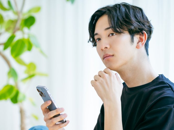 スマホを持って考え込む男性