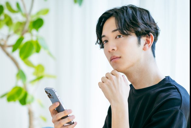 スマホを持って考え込む男性